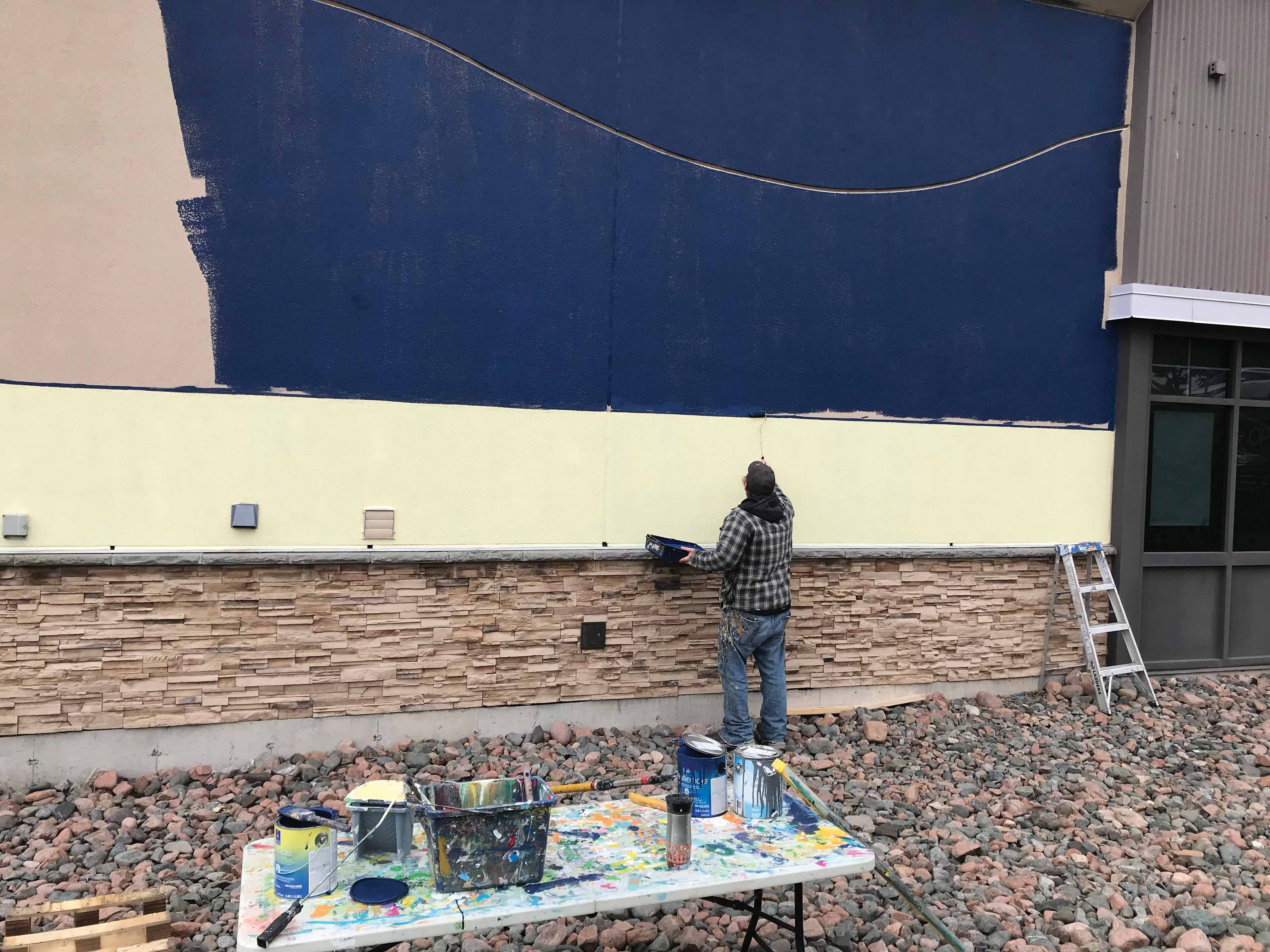 Artist, Jake Seibert, painting the mural