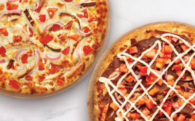 A flatlay of two pizzas beside each other on a marble countertop.