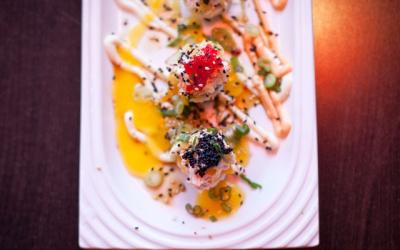 A flatlay of sushi drizzled in spicy mayo served on a plate.