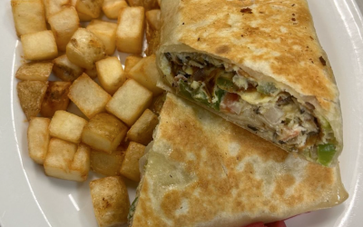 A breakfast wrap and hash browns from Roy's Restaurant, plated on a white plate